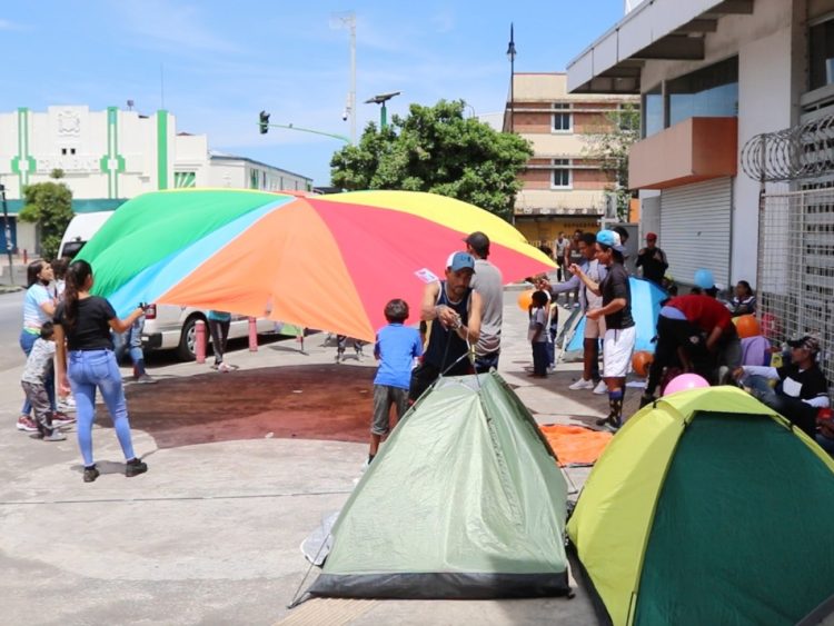 La imagen muestra a un grupo de personas migrantes venezolanas jugando en y su campamento en el centro de San José.